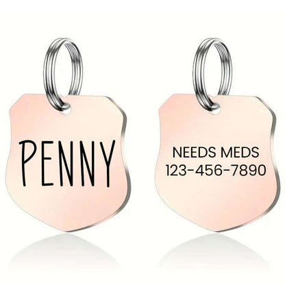 Personalized rose gold stainless steel shield-shaped pet ID tag with the name 'Penny' on one side and 'Needs Meds' with a contact number on the other; ideal for pets with medical needs.