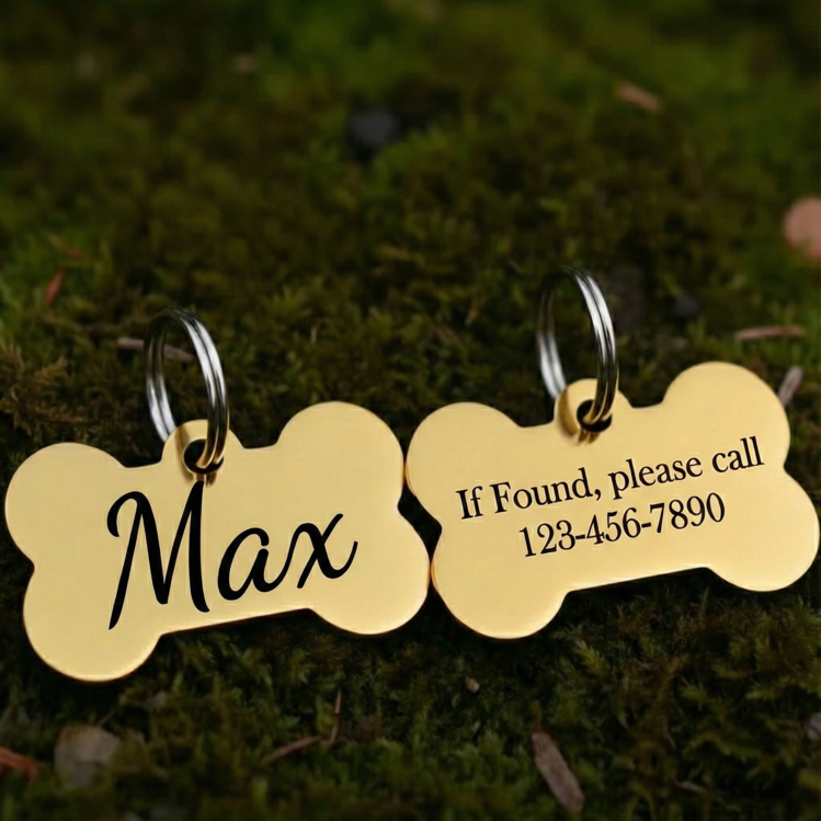 Gold bone-shaped pet tags with engraved text on a grass background