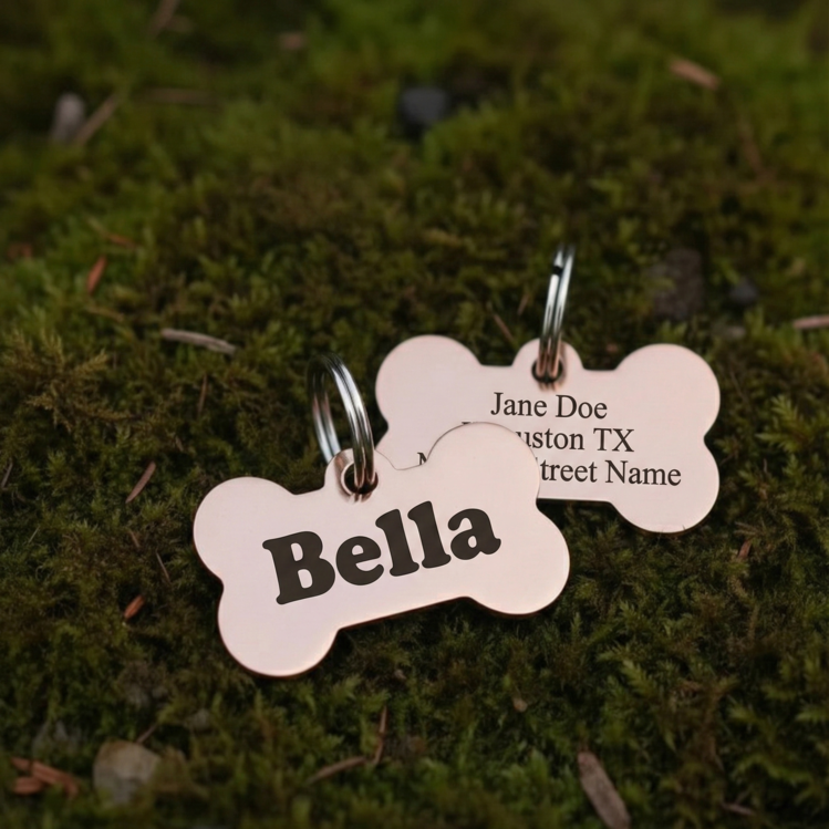 Two bone-shaped pet tags on a mossy background