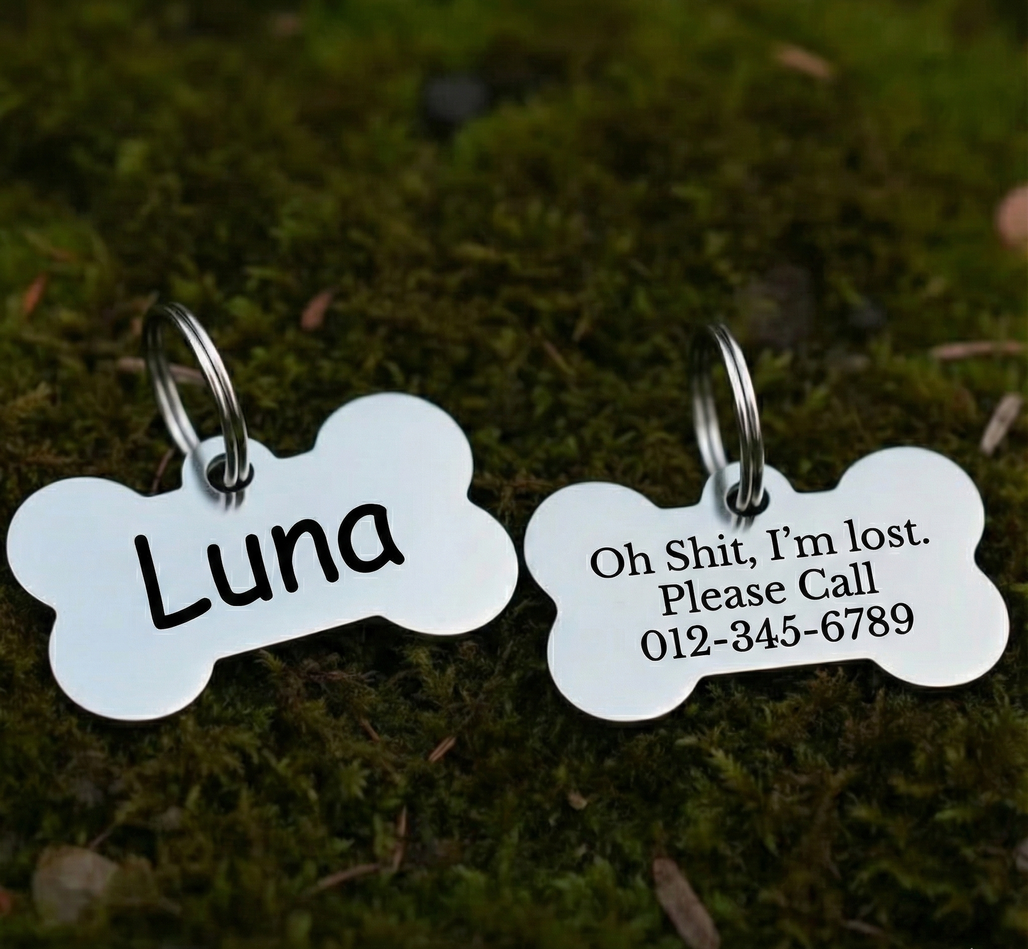 Two bone-shaped pet tags on a mossy background, one with 'Luna' and the other with a message and phone number.