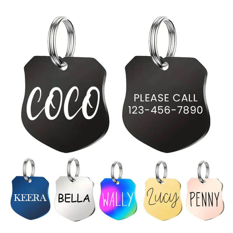 Variety of engraved stainless steel shield pet ID tags in black, silver, gold, rose gold, navy, and rainbow finishes featuring names like Coco, Keera, Bella, Lucy, Wally, and Penny with contact info. Ideal for secure dog identification.